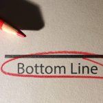 Bottom Line text circled in red pencil on textured paper surface