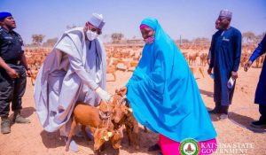 Katsina State governor taking a photo holding three goats with a woman