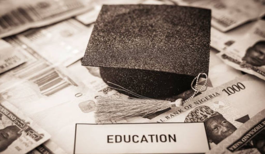 An academic graduation cap and a tag that is inscribed with 'education' on bunch of money