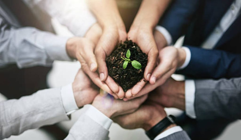 Various corporate workers holding a fertile earth (soil) representing CSR and sustainable environment