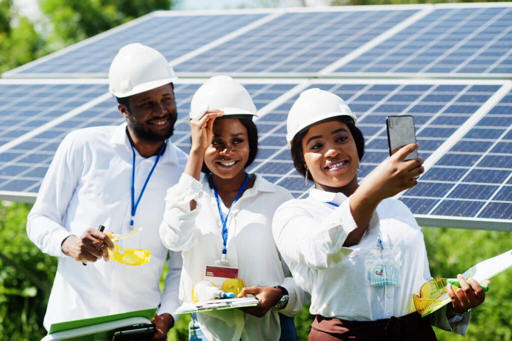 African engineers taking a selfie in front of solar panels, showcasing CSR and renewable energy efforts in Africa