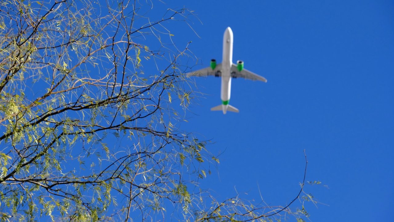 Airplane in the sky with green engines to show cleaner aviation fuel